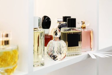 Dükkandaki raflarda farklı parfüm şişeleri ve parfümler var.