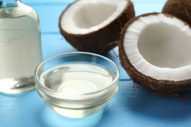 Organik hindistan cevizi pişirme yağı ve taze meyvelerin yarısı açık mavi ahşap masada, yakın plan.