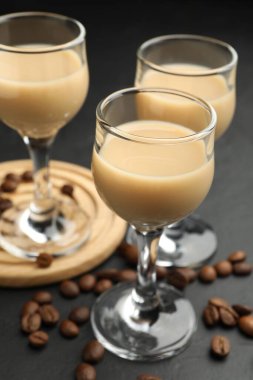 Bardakta kremalı kahve likörü ve siyah masada fasulye, yakın plan.