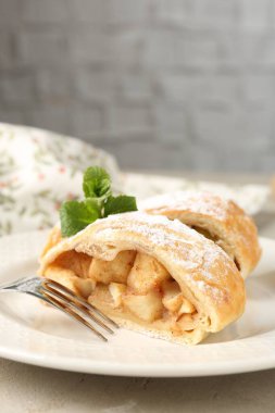 Lezzetli elmalı turta parçaları pudra şekeri, nane ve çatal ile yakın plan, gri masada.