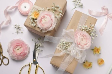 Çiçekçi. Beyaz arka planda kutular, çiçekler, kurdele ve makas düz konum