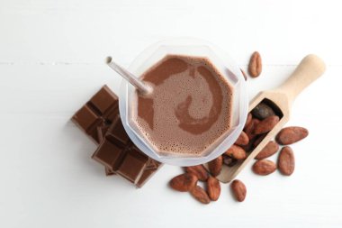 Lezzetli çikolatalı süt, barlar ve kakao çekirdekleri beyaz ahşap masa, düz uzanmış