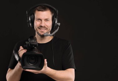 Profesyonel video kamerası ve kulaklığı olan adam siyah arkaplanda, metin için boşluk