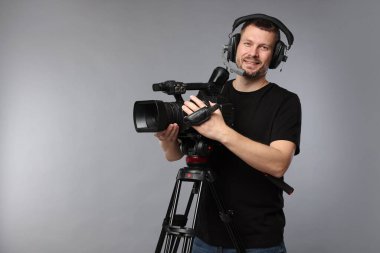 Profesyonel kamera ve kulaklıklı adam gri arka planda, metin için boşluk