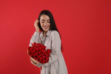 Kırmızı arka planda lale buketi olan mutlu kadın, mesaj için yer var. 8 Mart kutlamaları
