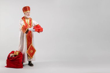 Açık gri arka planda hediyelerle dolu bir çuval dolusu Aziz Nicholas. Metin için boşluk