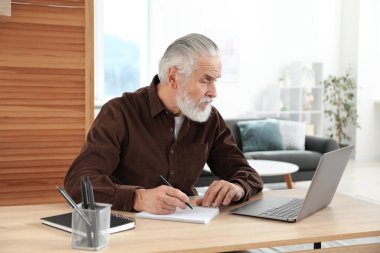 Üst düzey adam içeride masa başında öğrenirken not alıyor. Kendi kendine çalışma.