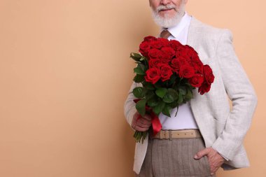 Bej arka planda kırmızı gül buketi olan son sınıf öğrencisi, yakın plan. Metin için boşluk