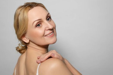 Gri arka planda gülümseyen orta yaşlı kadın. Metin için boşluk