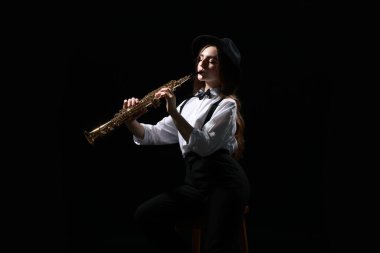 Koyu arkaplanda soprano saksafon çalan müzisyen.