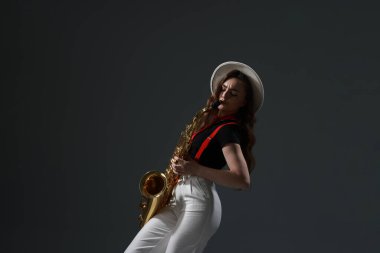 Gri arka planda saksafonu olan profesyonel bir müzisyen.