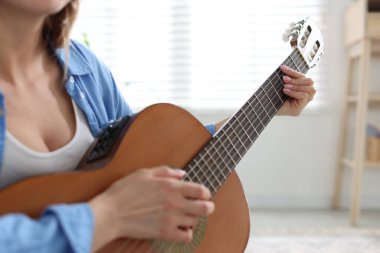 Evde gitar çalan genç bir kadın, yakın plan.
