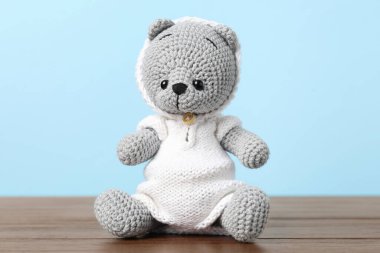 Ahşap masada açık mavi arka planda sevimli örülmüş oyuncak ayı.