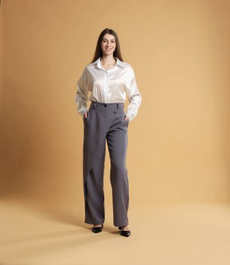 Bej arka planda şık giyinmiş güzel bir kadın.