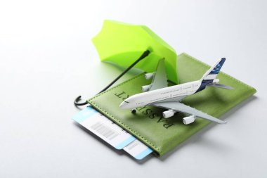 Seyahat sigortası. Uçak modeli, pasaport, küçük şemsiye ve açık gri arka planda biletler, yakın plan.