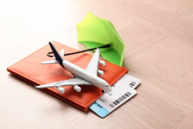 Seyahat sigortası. Uçak modeli, pasaport, küçük şemsiye ve biletler ahşap masada, yakın plan.