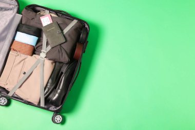 Elbiseler, ayakkabılar, pasaport ve açık yeşil arka planda bilet, üst manzara. Metin için boşluk