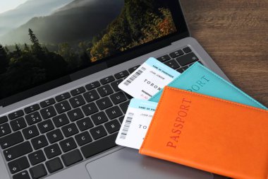 Pasaportlar, uçuş biletleri ve dizüstü bilgisayar ahşap masanın üstünde.