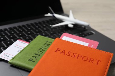 Pasaportlar, uçuş biletleri, uçak modeli ve dizüstü bilgisayar masada, yakın plan.