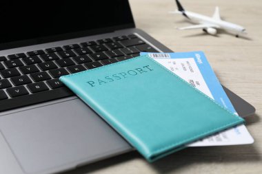 Pasaport, uçuş bileti, uçak modeli ve laptop ahşap masada, yakın plan.