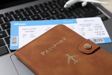 Pasaport, uçuş bileti, uçak modeli ve dizüstü bilgisayar masada, yakın plan.