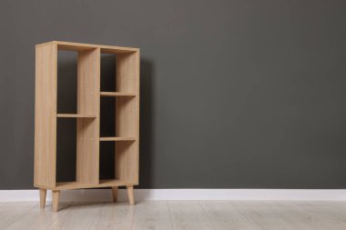 Empty shelving unit near grey wall indoors, space for text