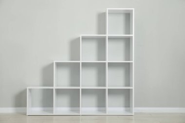 Açık gri duvarın yanındaki boş raf ünitesi.