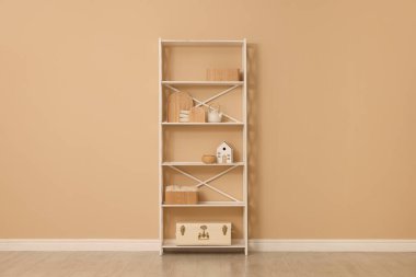 Shelving unit with decor near beige wall indoors