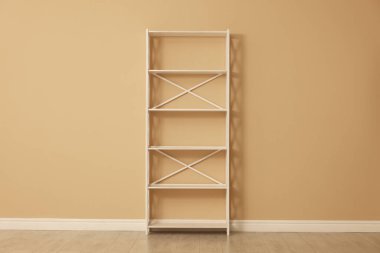 Bej duvarın yanındaki boş raf ünitesi.