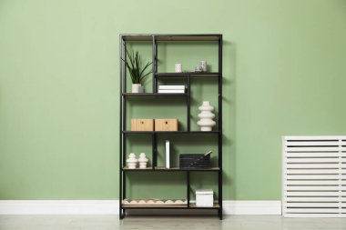 Salon içinde zeytin duvarının yanında farklı dekorasyonu olan ahşap raf ünitesi.