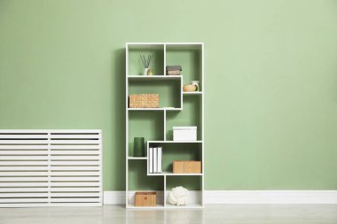 Salon içinde zeytin duvarının yanında farklı dekorasyonu olan ahşap raf ünitesi.