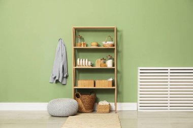 Salon içinde zeytin duvarının yanında farklı dekorasyonu olan ahşap raf ünitesi.