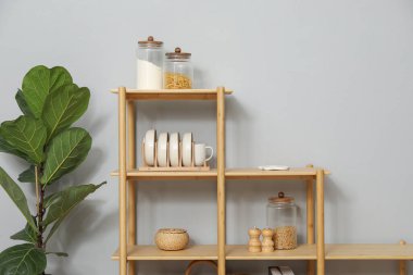 Açık gri duvarın yanında farklı dekorasyona sahip ahşap raf ünitesi.