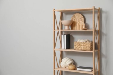 Açık gri duvarın yanında farklı dekorasyona sahip ahşap raf ünitesi. Metin için boşluk