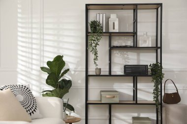 Beyaz duvarın yanında dekorasyonu olan şık raf ünitesi.