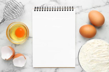 Boş yemek tarifi kitabı, çırpma, un ve yumurta beyaz mermer masa, üst manzara. Tasarım için model