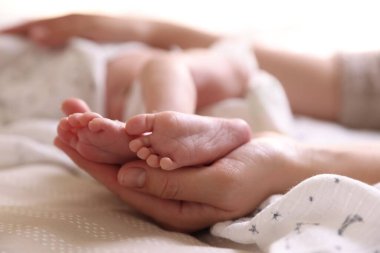 Anne, küçük bebeği evde, yatağında, yakın plan.