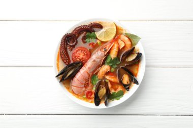 Lezzetli deniz ürünleri çorbası, beyaz ahşap masada, üst manzara.