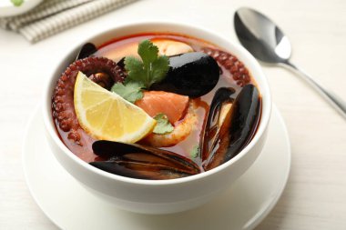 Hafif ahşap masada servis edilen lezzetli deniz ürünleri çorbası, yakın plan.