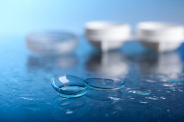 Mavi ayna yüzeyine bir çift kontakt lens, kap ve su damlası, seçici odak