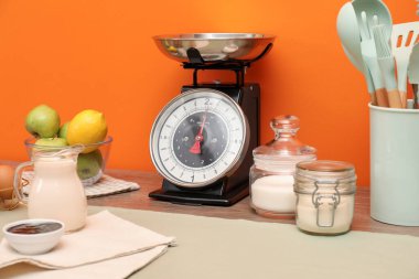 Kitchen scale, products and cooking utensils on wooden table