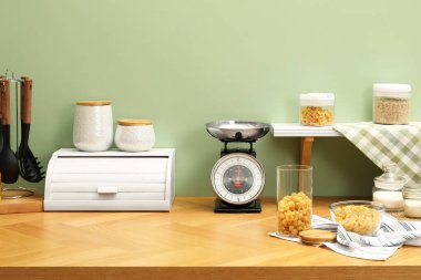 Kitchen scale, products and cooking utensils on wooden table