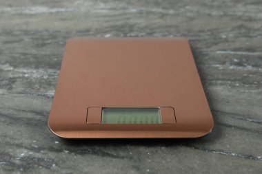Gri mermer masa üzerinde modern elektronik mutfak terazisi, yakın plan.