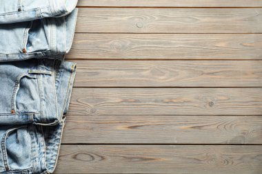 Different stylish jeans on wooden background, flat lay. Space for text
