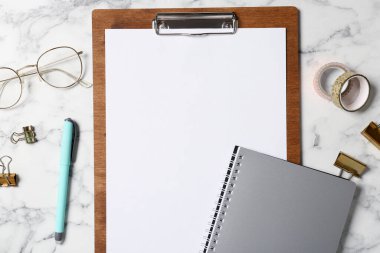 Beyaz mermer zemin üzerinde boş kağıt ve pano ile düz kompozisyon yatıyordu. Metin için boşluk