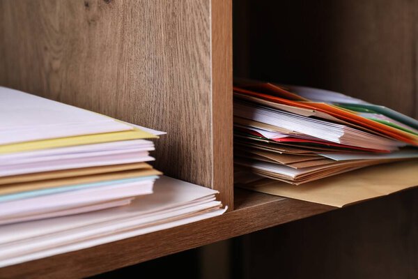 Различные бумажные конверты на деревянных полках в почтовом отделении, крупным планом