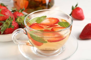 Aromatik çilekli meyve çayı ve beyaz masada nane şekeri, yakın plan.