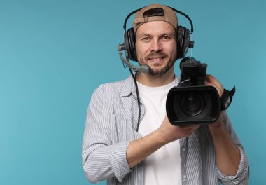 Açık mavi arka planda profesyonel video kamerası ve kulaklığı olan adam, metin için boşluk