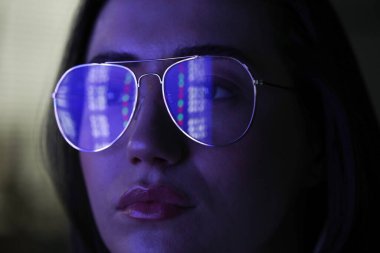 Siyah arka planda yansıması olan gözlüklü genç bir kadın, yakın plan.