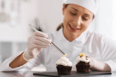 Şekerci, mutfakta bir parça çikolatayla kek dekore ediyor, seçici odaklı.